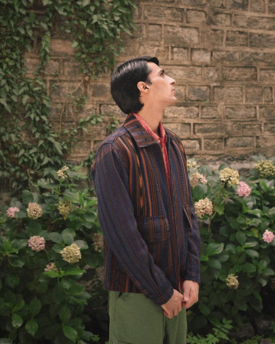 Portrait in camo-textured tailoring against a botanical set.