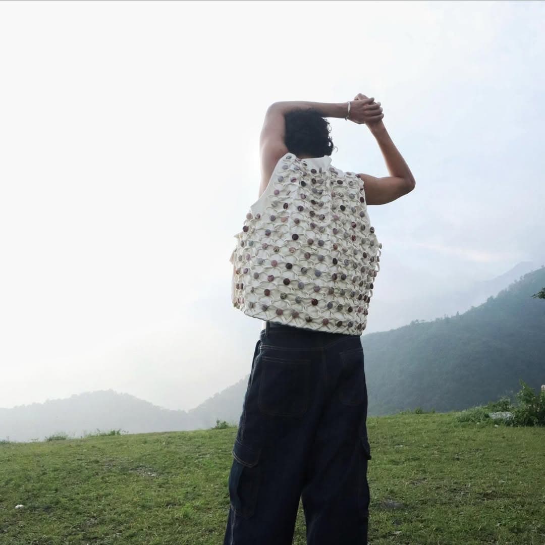 Back-facing mountain portrait with textured white vest.