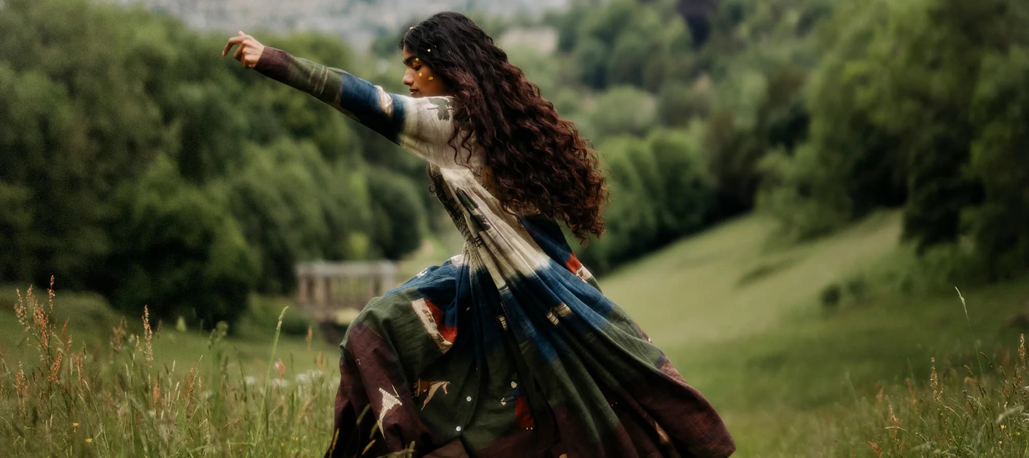 Portrait of a model in striped shirt and cap seated above a valley and temple backdrop